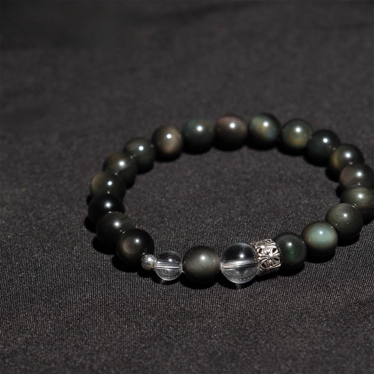Flat lay of spiritual healing stone bracelet with obsidian and crystal charm