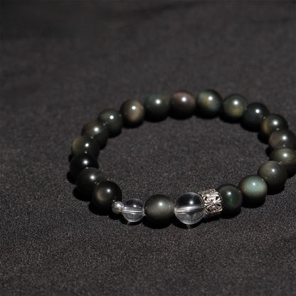 Flat lay of spiritual healing stone bracelet with obsidian and crystal charm